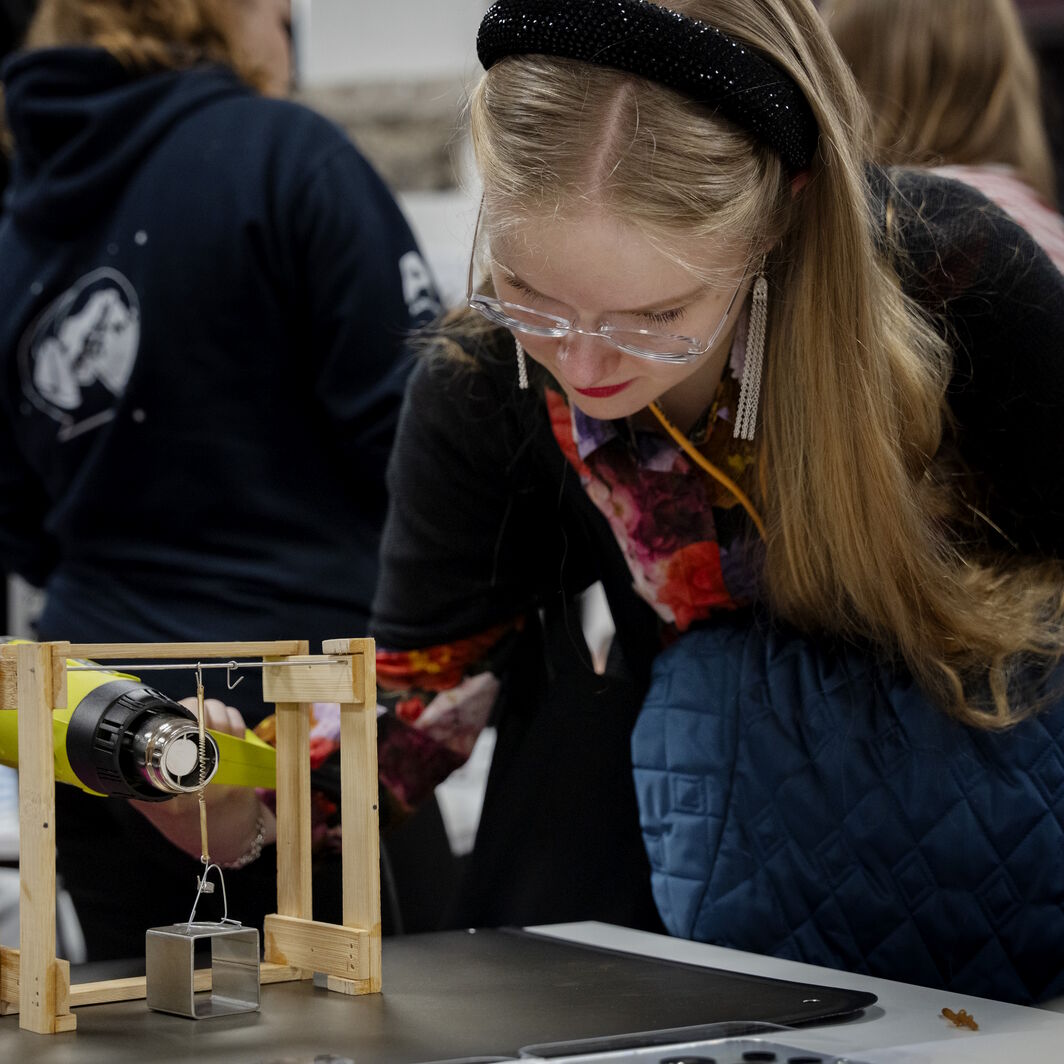 Event participant heating up a string made of heat-active material with a heatgun.