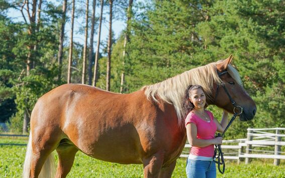 Maija Leinonen standing with her horse.