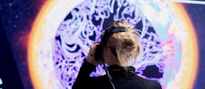 Young woman using VR goggles, standing in front of a colorful background